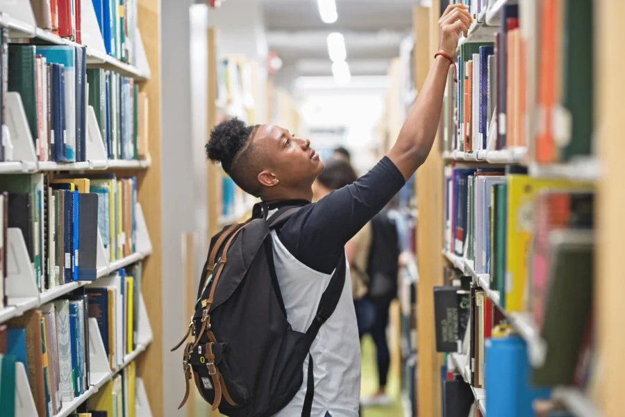 Student som gör efterforskningar i biblioteket för sina studier och för att säkerställa finansiering av studenternas framgång.