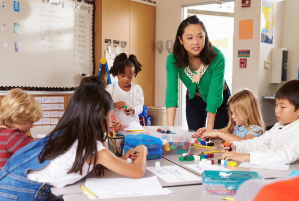 Student teacher working closely with kindergarten students