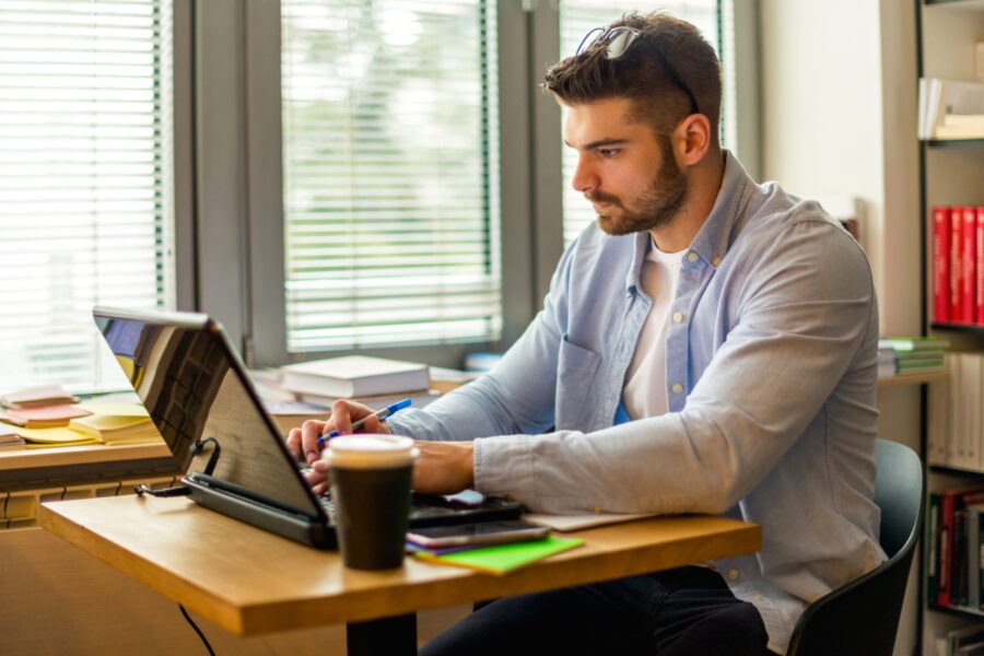 Studente maschio che studia online mentre è a casa sua